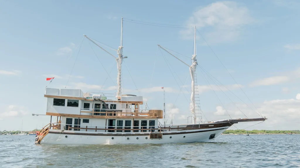 A phinisi under full sail in Komodo waters at golden hour