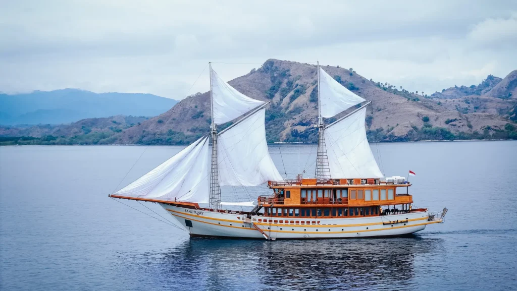 A phinisi under full sail in Komodo waters at golden hour